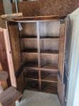Walnut stained wooden pantry cabinet with shelves and doors.
