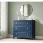 Dark blue wooden dresser with three drawers and round knobs in a modern room.