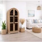 Elegant arched wooden display cabinet with glass doors in modern living room.