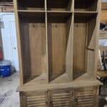 Wooden mud room cabinet with hooks and storage compartments for coats and shoes.