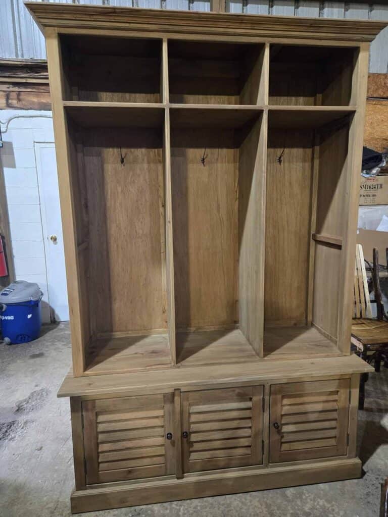 Wooden mud room cabinet with hooks and storage compartments for coats and shoes.