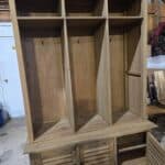 Wooden mud room cabinet with coat hooks and storage compartments.