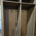 Wooden mud room cabinet with hooks for coats and storage compartments.